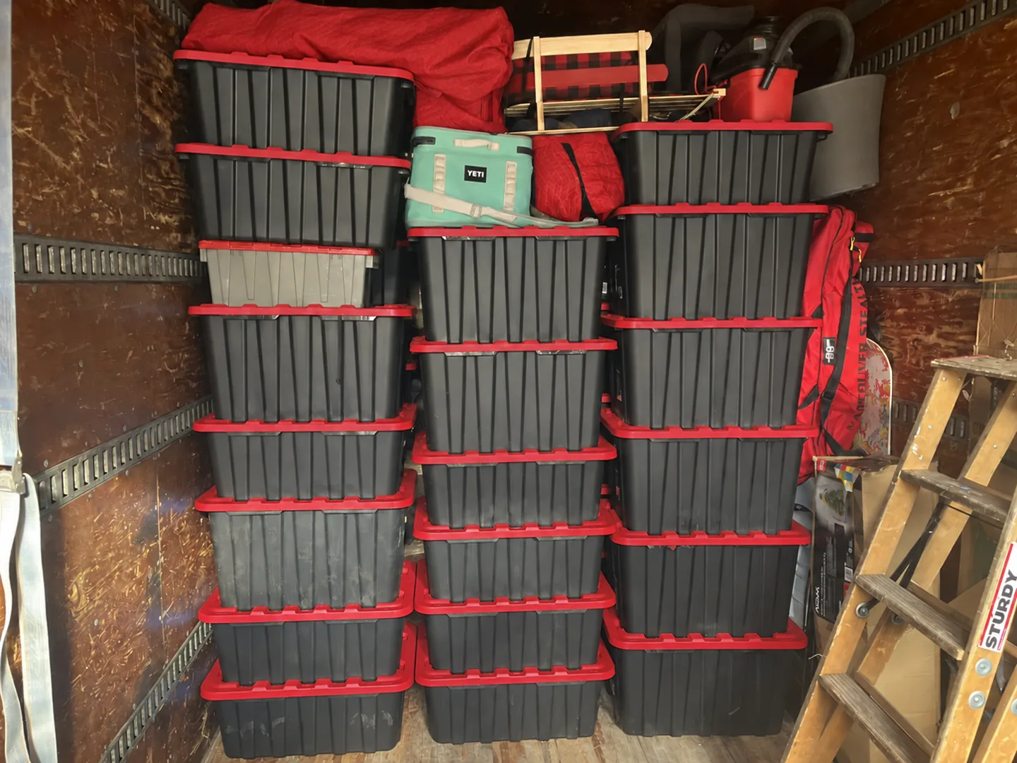Organized moving bins with red lids inside a real moving truck