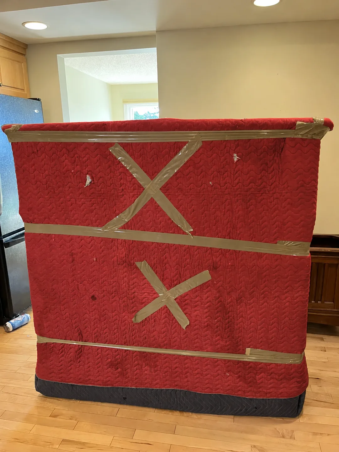 A large furniture piece secured in red quilted moving materials