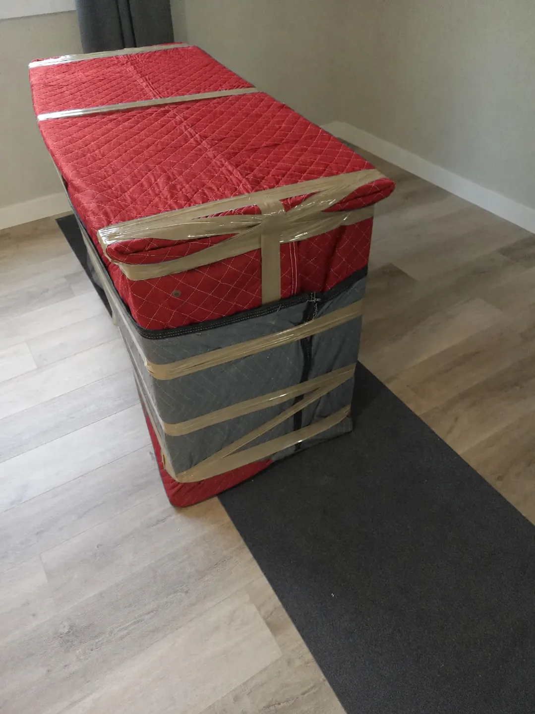 A wrapped furniture piece on a charcoal floor runner