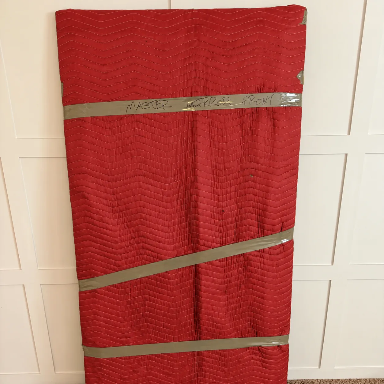 A mirror wrapped and secured in red protective blankets